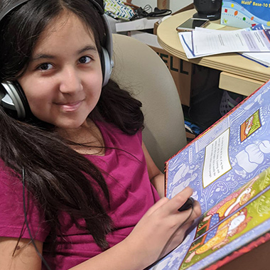 student wearing headset and reading a book